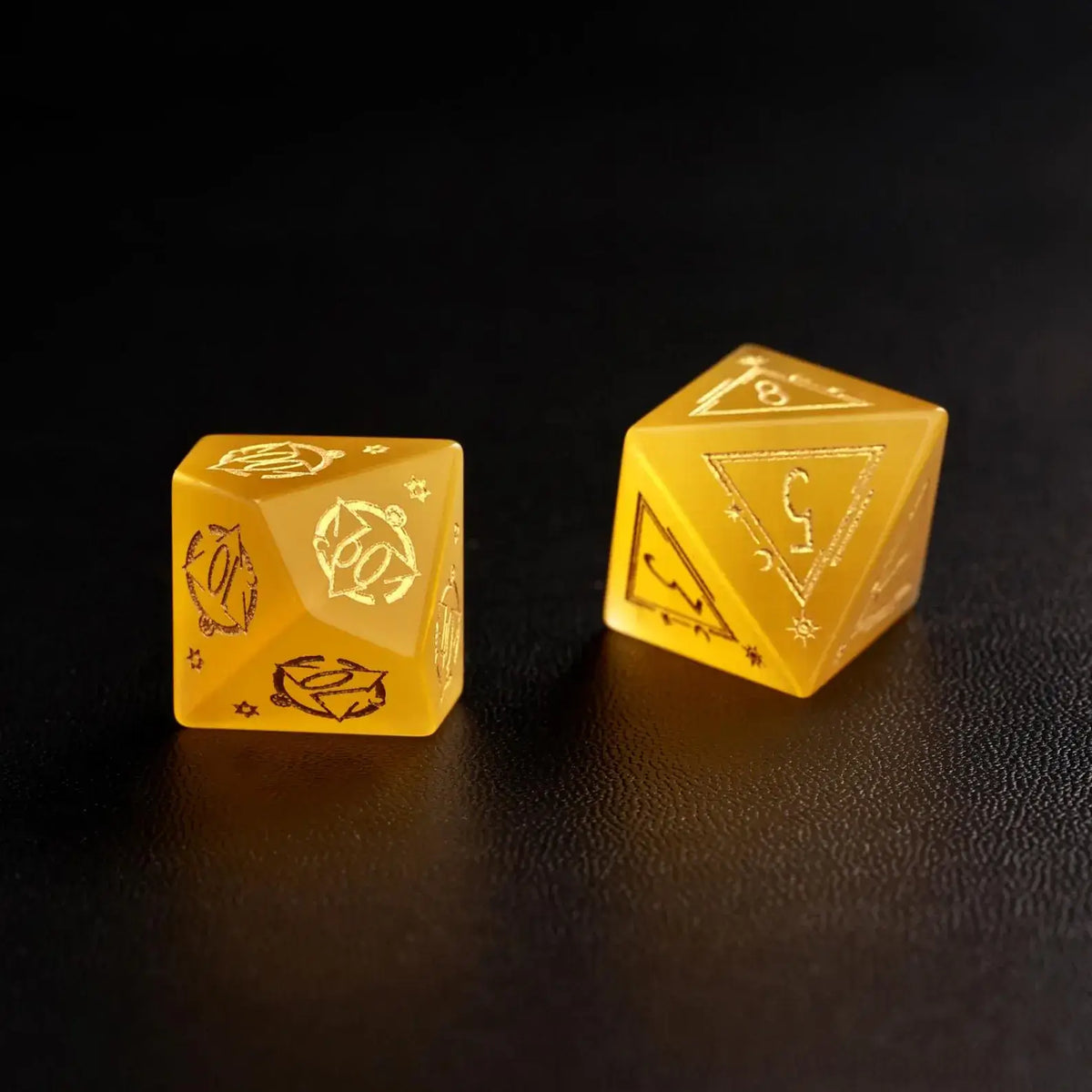Two Handcrafted DND Yellow Cat's Eye Polyhedral Dice (D4 and D6) resting on a black surface, emphasizing the quality of the natural stone material.