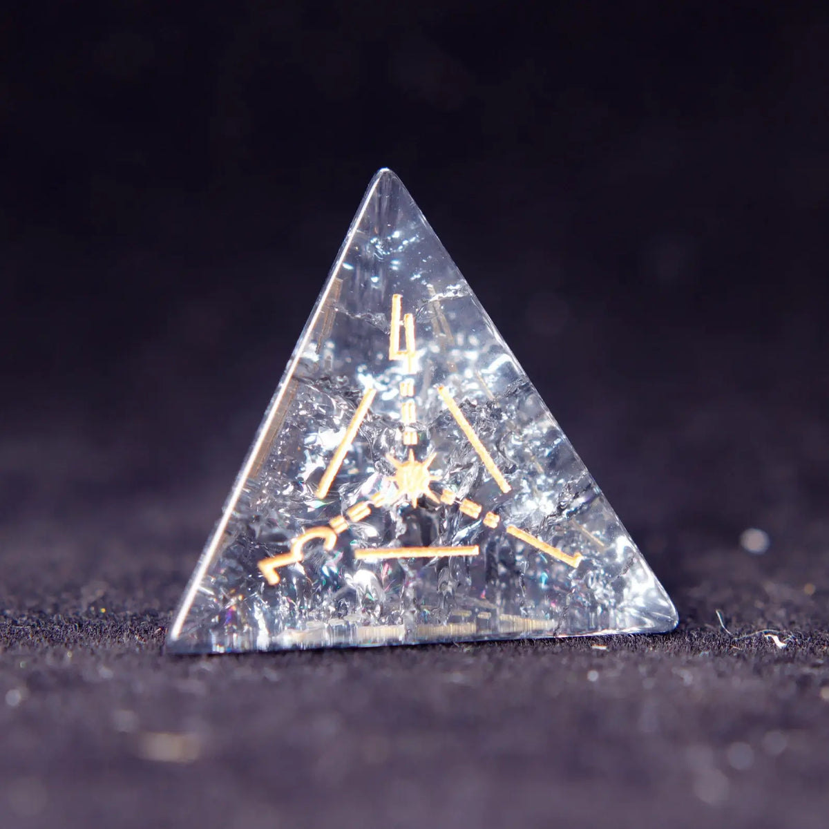 Single Black Crystal D4 dice with sharp edges and gold numbers, isolated on dark background