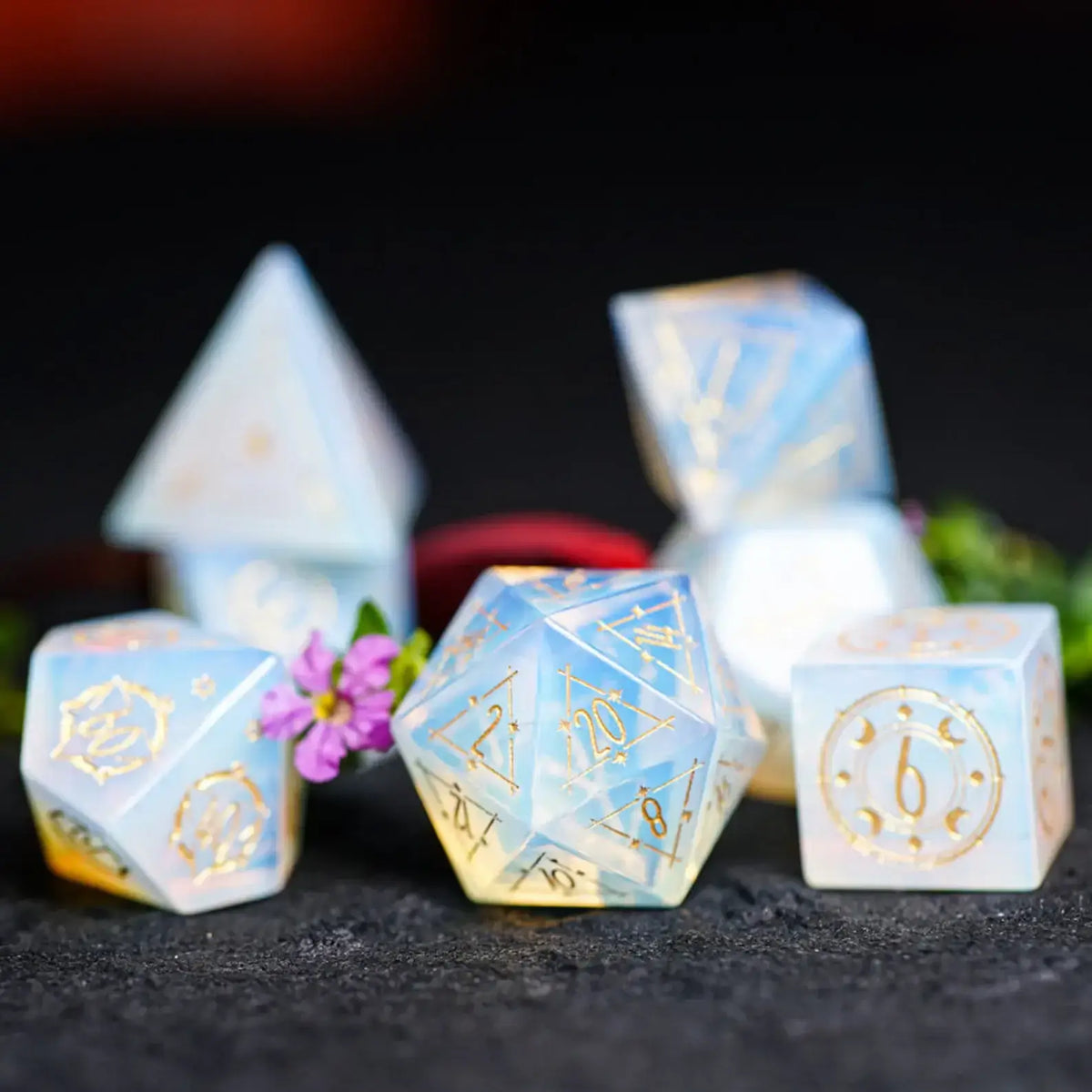 Complete D&D Opalite Engraved Dice Set with astrology symbols laid out on a dark velvet surface.