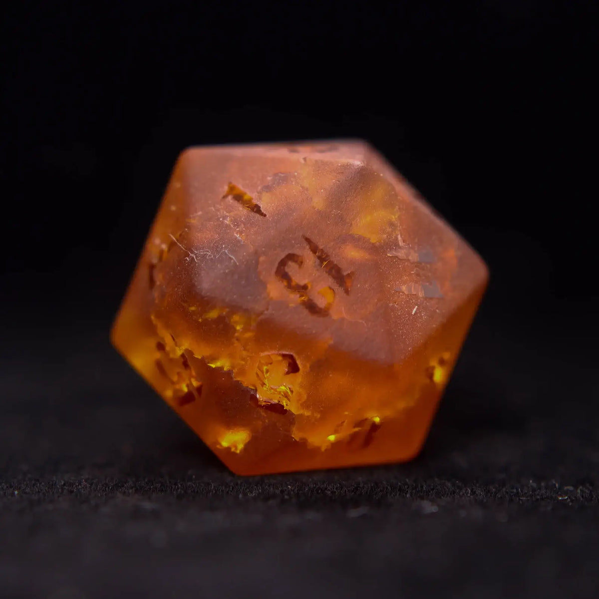 Close up of an orange Gemstone Dice Set d20 with sharp edges