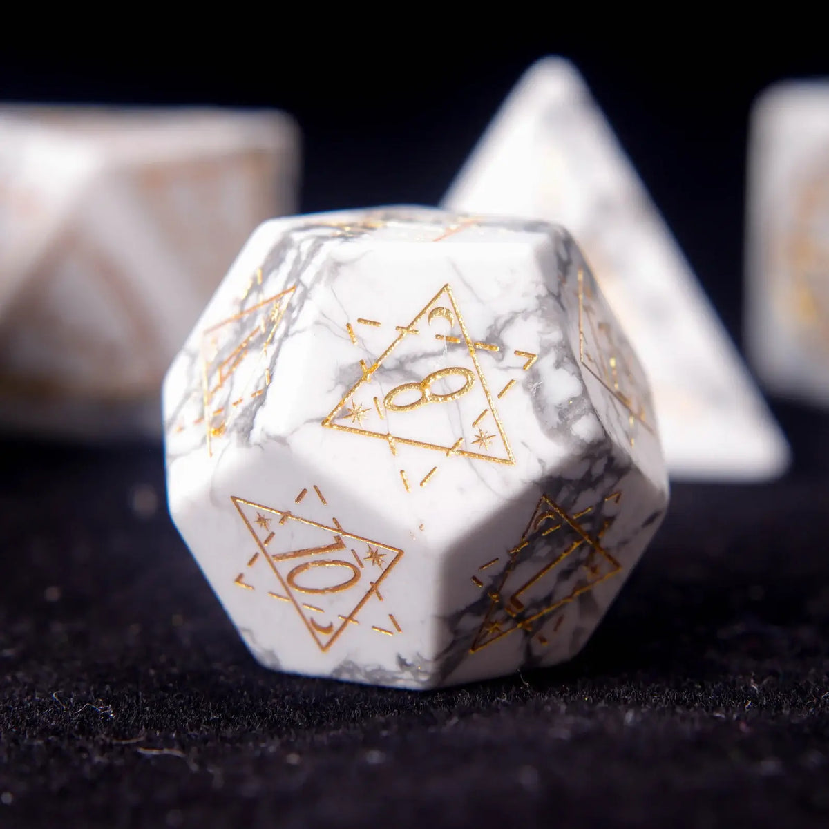 Intricate engraved celestial symbols on a White Howlite D12 die.