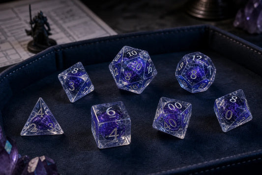 Seven transparent blue-violet liquid core polyhedral dice resting in a padded DND dice tray
