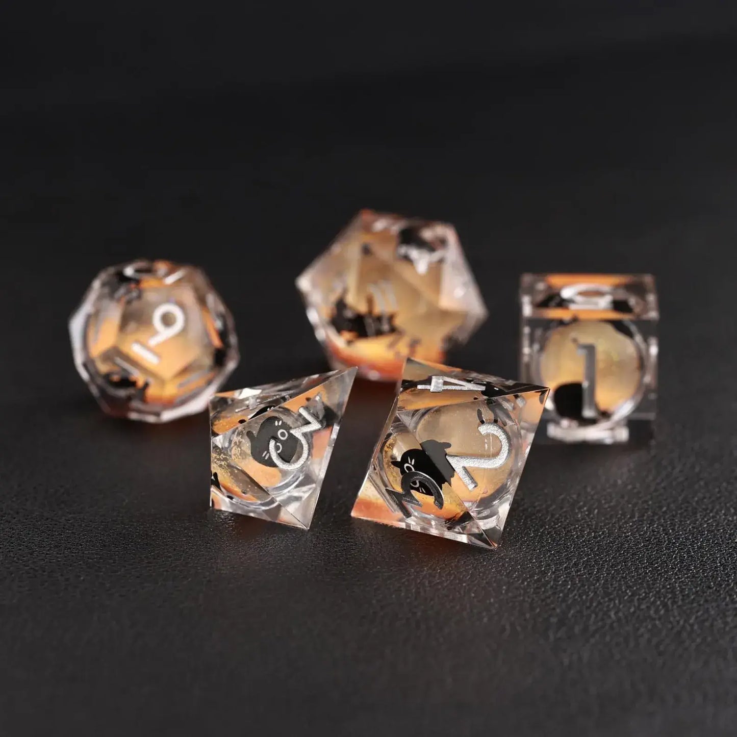 Comparison view of the d4 and d20 dice from the Orange Swirl Liquid Core Dice Resin Set, including the black cat