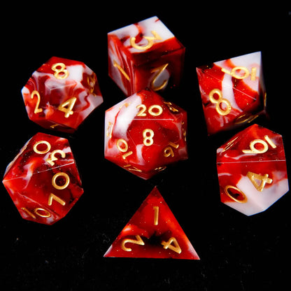 A set of seven red and white mixed resin dice lay flat on a black velvet background, with fine white glitter like snow.