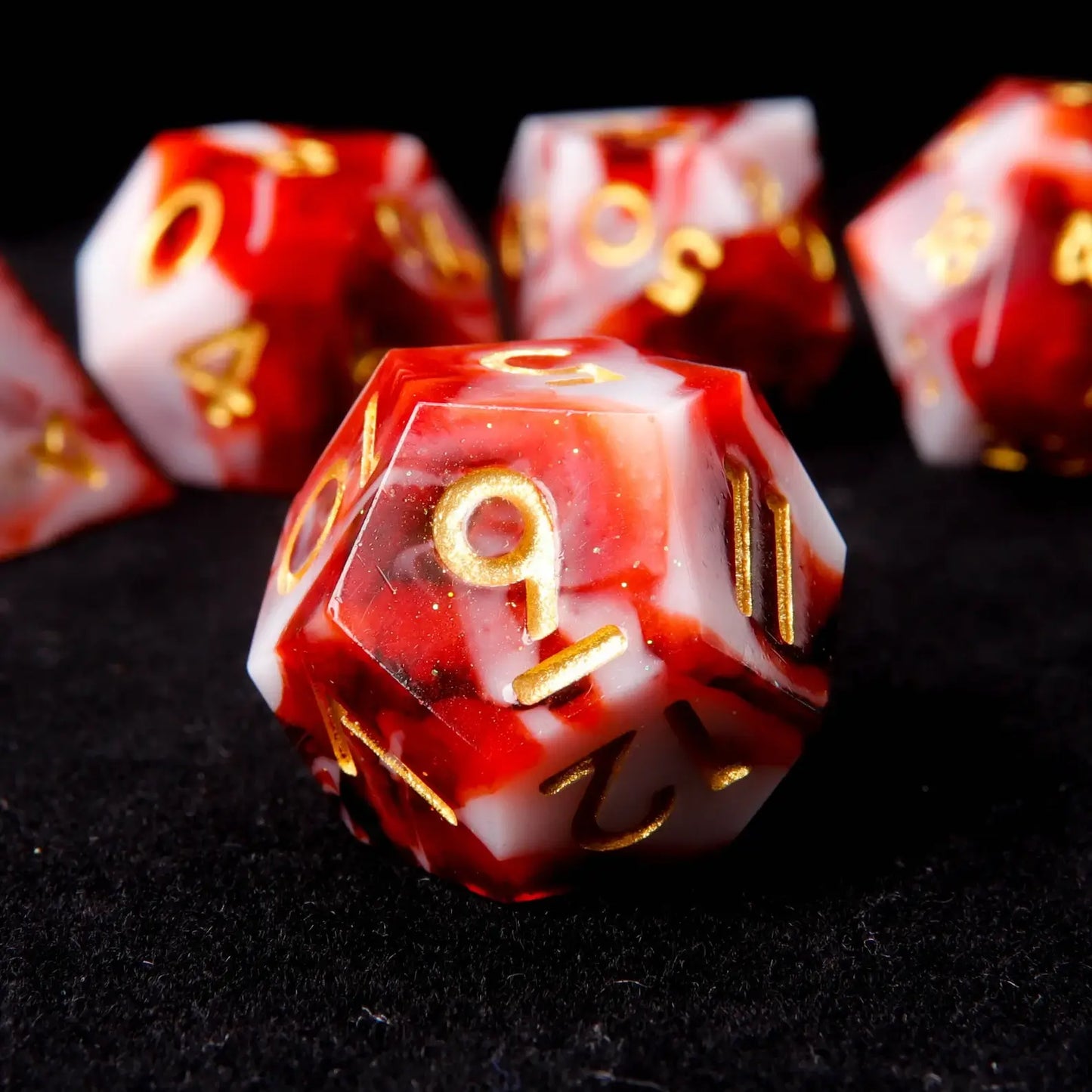A red and white resin D12 is placed on a black velvet background, adorned with small white sequins like snowflakes.