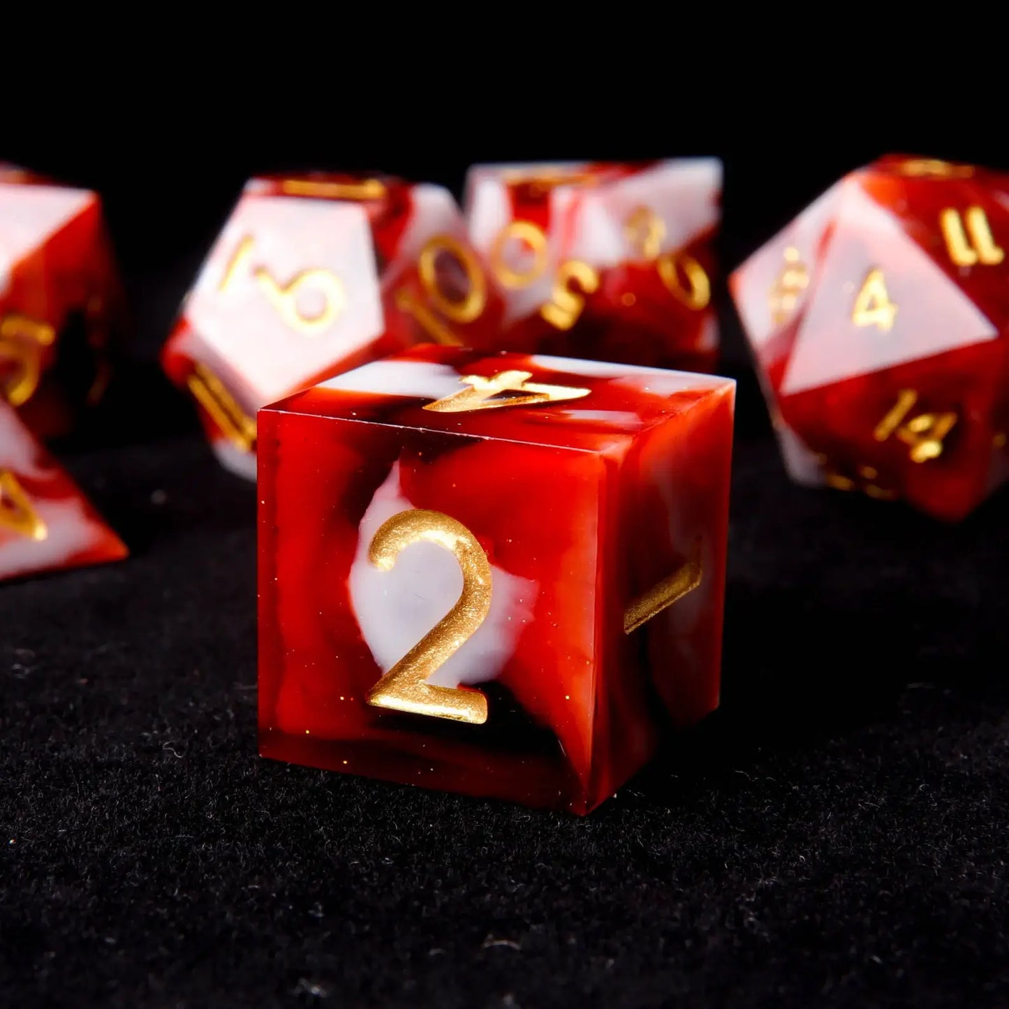 A red and white resin D6 is placed on a black velvet background, adorned with small white sequins like snowflakes.
