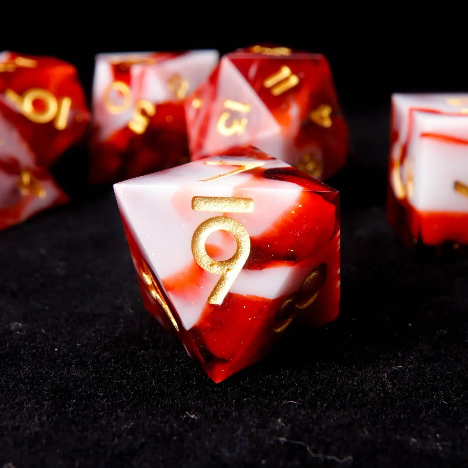 A red and white resin D8 is placed on a black velvet background, adorned with small white sequins like snowflakes.