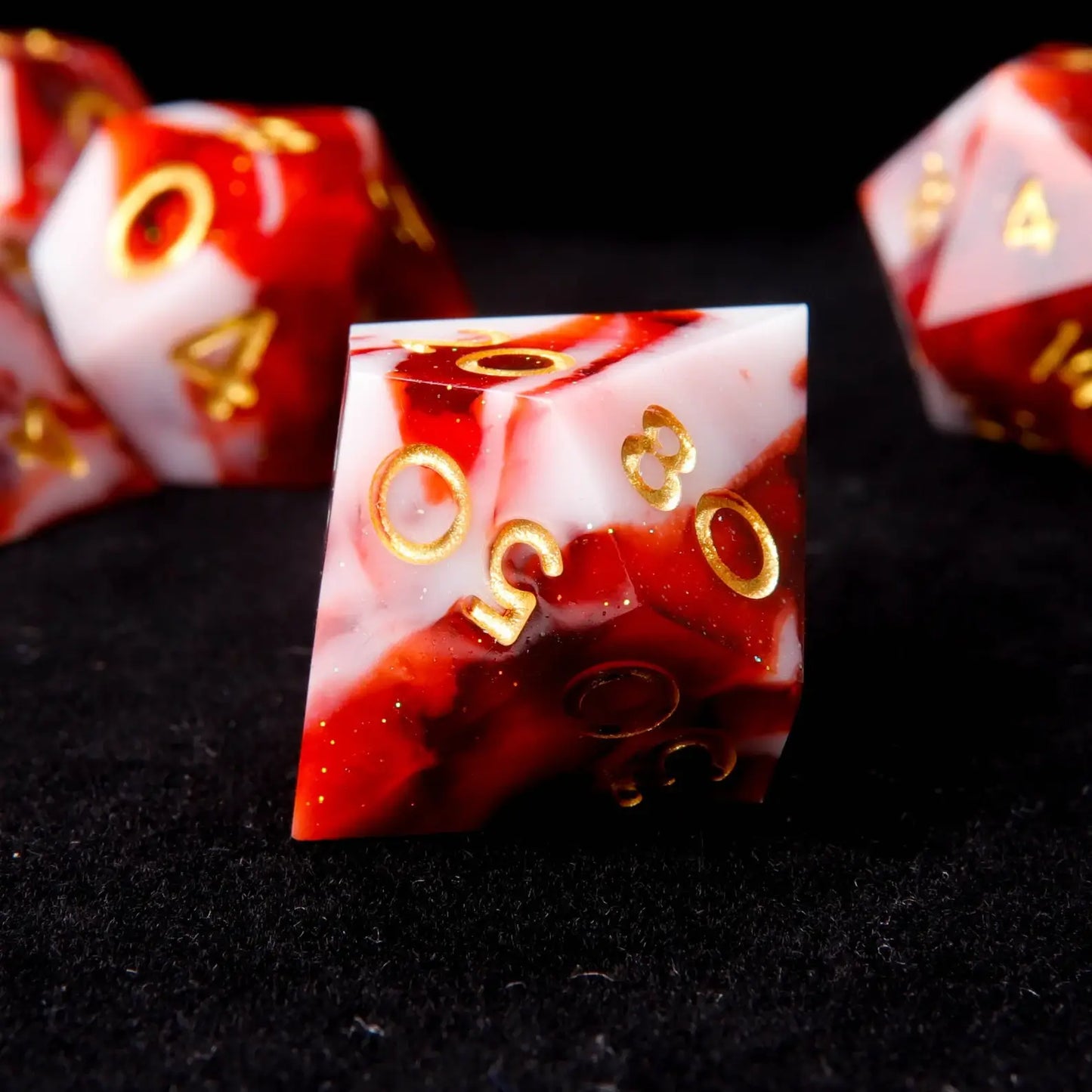 A red and white resin D% is placed on a black velvet background, adorned with small white sequins like snowflakes.