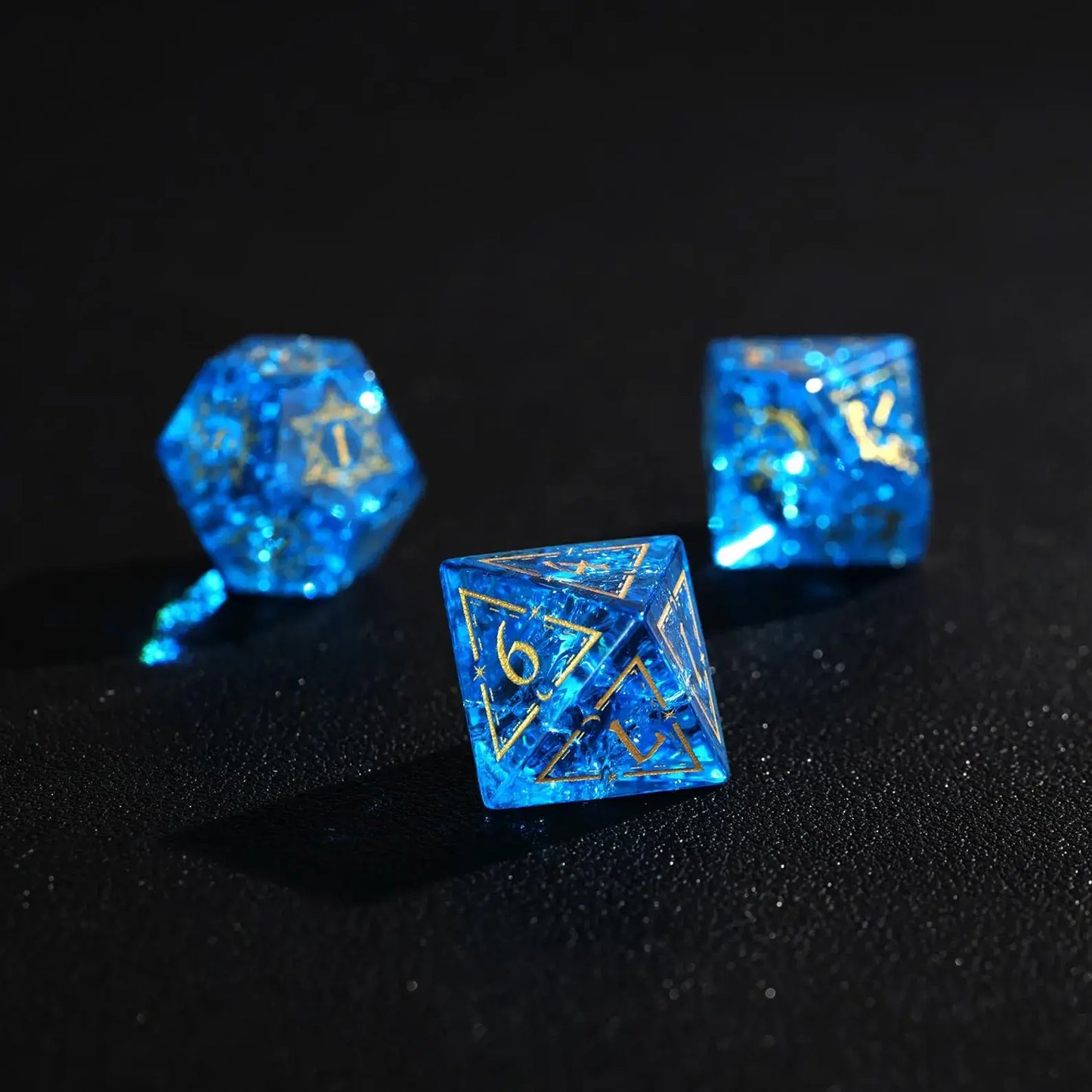 Three Blue Glass D6 dice side-by-side, emphasizing the clear gold numbers and the demon eye engraving.