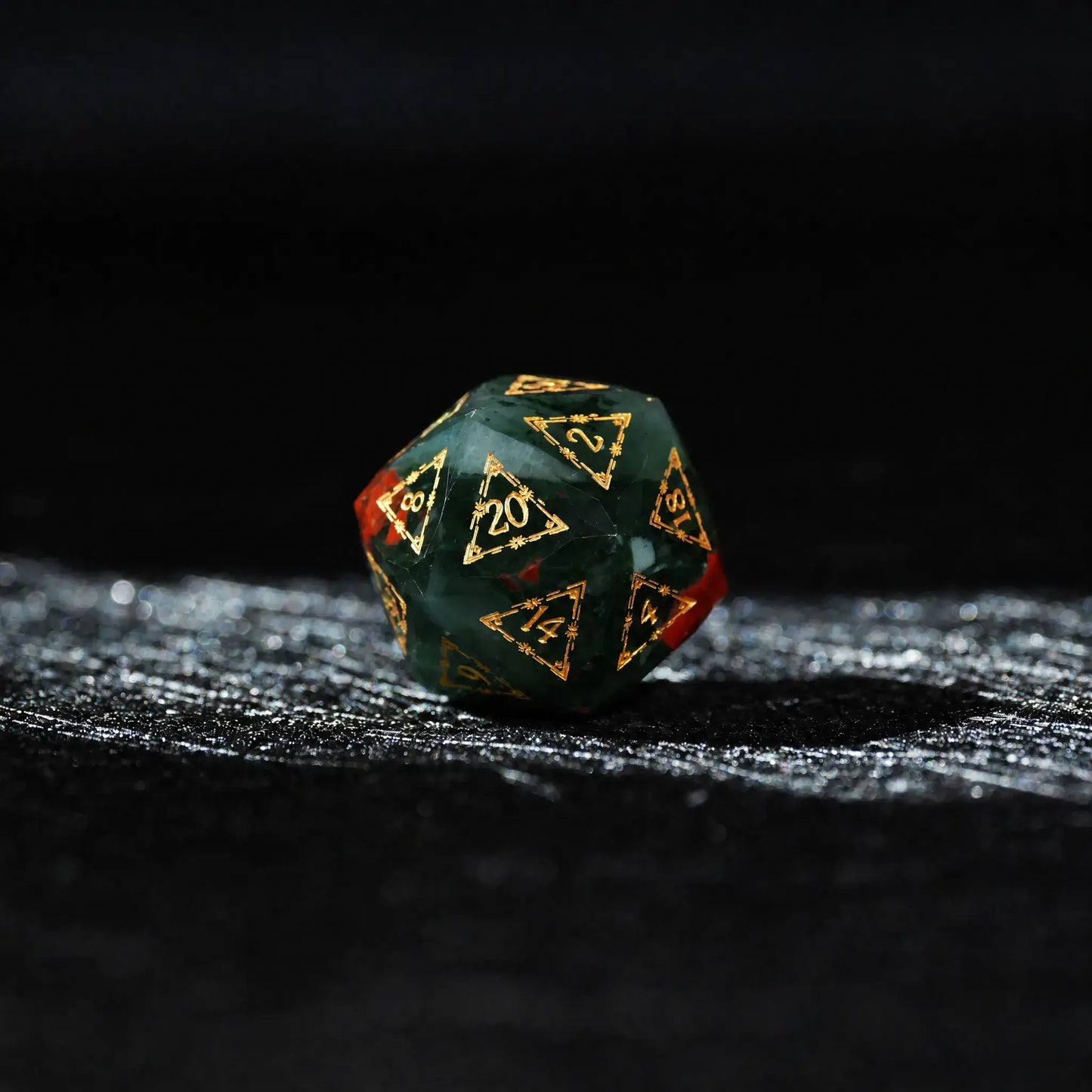 Celestial Bloodstone Gemstone Dice Set, single d20 on a dark tabletop background
