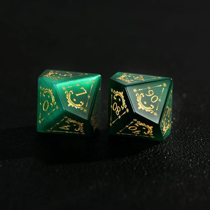 Two Handcrafted DND Dare Green Cat's Eye Polyhedral Dice (D4 and D6) featuring Gold Inking, resting on a black surface, emphasizing the quality and rich color.