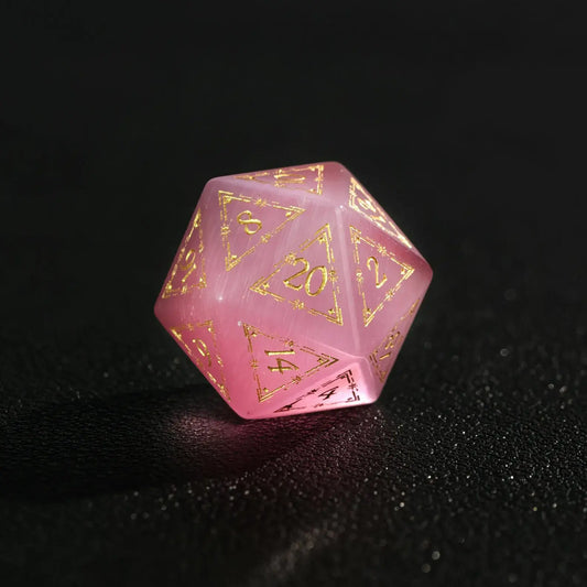 Close-up of a single Pink Cat's Eye Gemstone Dice D20, a handcrafted DND polyhedral die on a dark black background, highlighting the distinct cat's eye light effect.