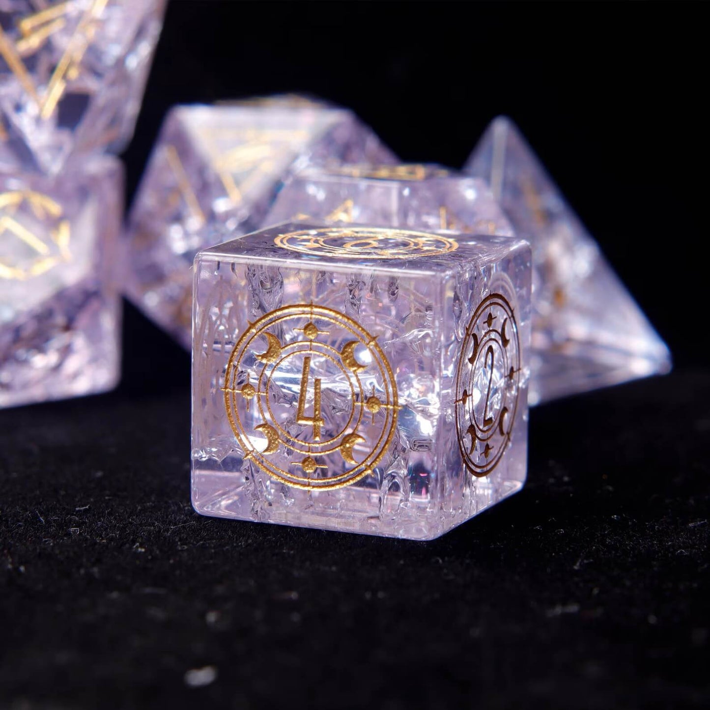 Three Pink Glass D6 dice side-by-side, emphasizing the clear gold numbers and the intricate demon eye engraving.