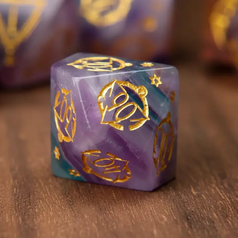Detailed image of a single purple fluorite D10 percentile die, showcasing its gemstone clarity and engraving on a wooden table.