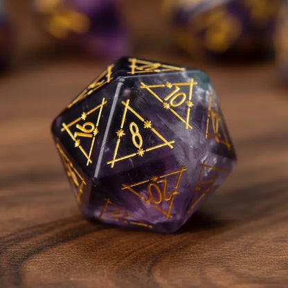 Single, beautifully engraved purple fluorite D20 die isolated on a walnut wood table background.