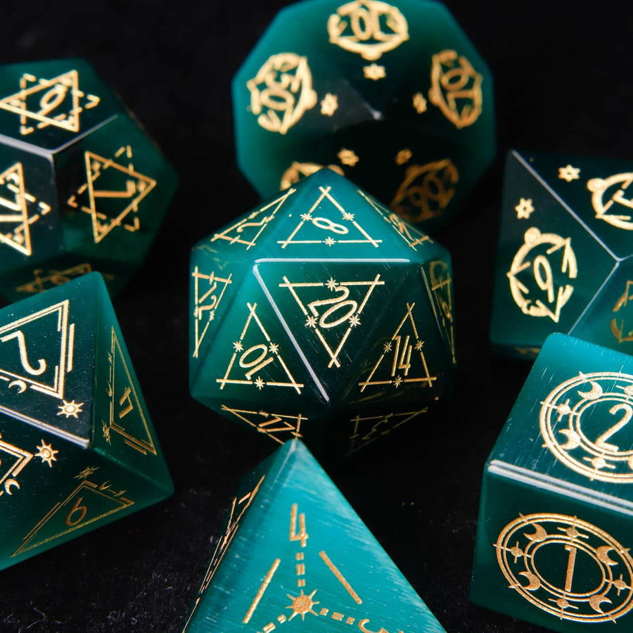 Complete URDdice Dark Green Cat's Eye Gemstone Dice Set. All seven engraved polyhedral dice displayed on a black background, showcasing their mystical chatoyant luster.