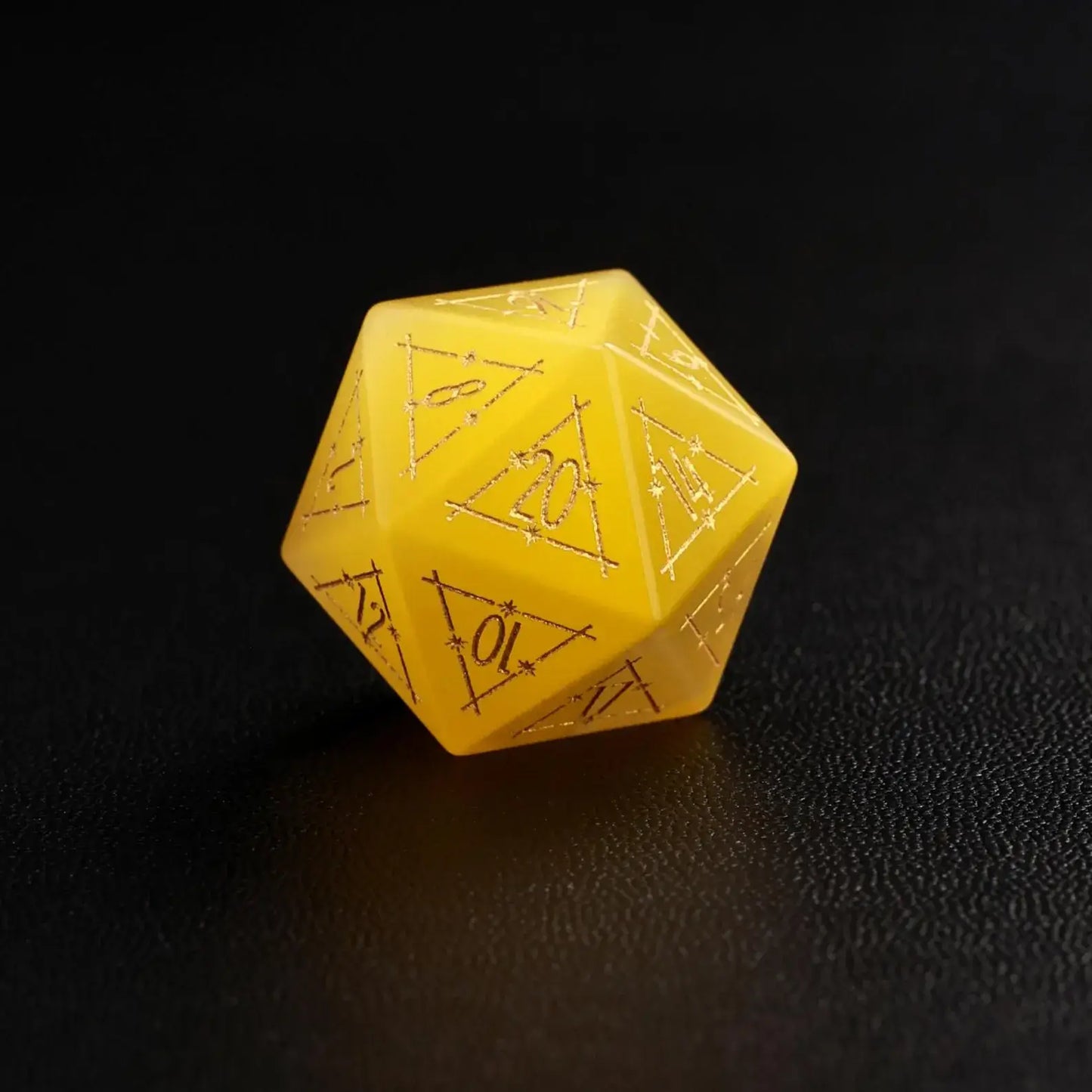 Close-up of a single Yellow Cat's Eye Gemstone Dice D20, a handcrafted DND polyhedral die on a dark black background, highlighting the distinct yellow cat's eye flash effect.