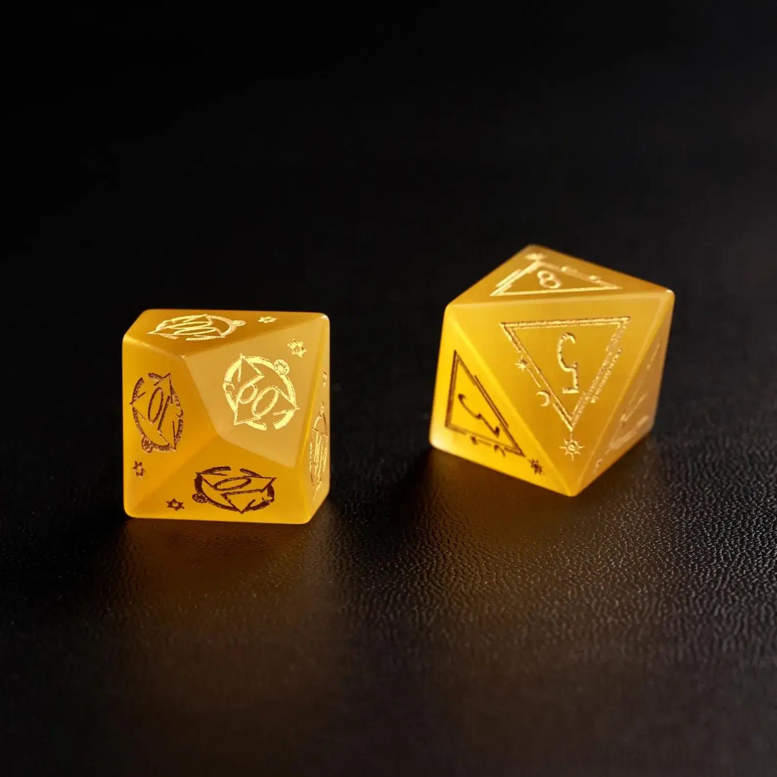 Two Handcrafted DND Yellow Cat's Eye Polyhedral Dice (D4 and D6) resting on a black surface, emphasizing the quality of the natural stone material.