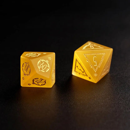Two Handcrafted DND Yellow Cat's Eye Polyhedral Dice (D4 and D6) resting on a black surface, emphasizing the quality of the natural stone material.
