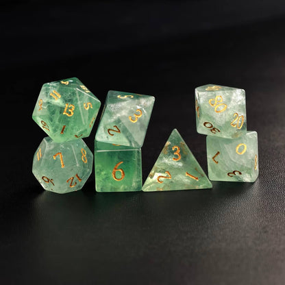 Photo of all 7 polyhedral dice (D4, D6, D8, D10, D%, D12, D20) arranged in a neat line on a dark surface.