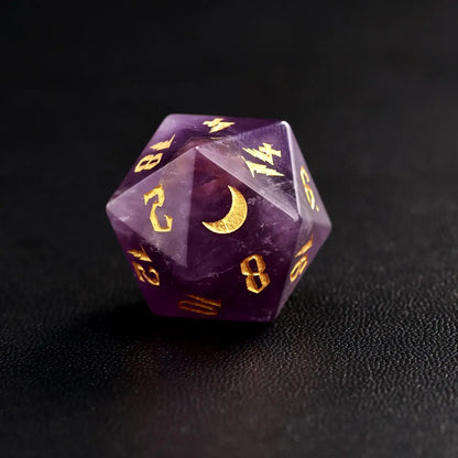 Close-up of a single natural amethyst D20 die with gold moon engravings and numbers on a premium black leather surface.