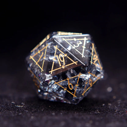 Close-up of a sharp-edged Black Crystal D20 dice with luminous gold engraved numbers against black backdrop