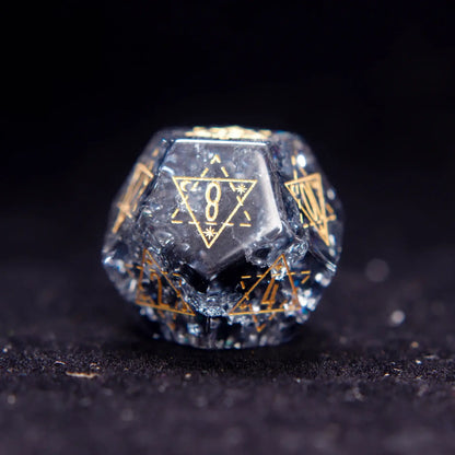 Single Black Crystal D12 dice with sharp edges and gold numbers, isolated on dark background