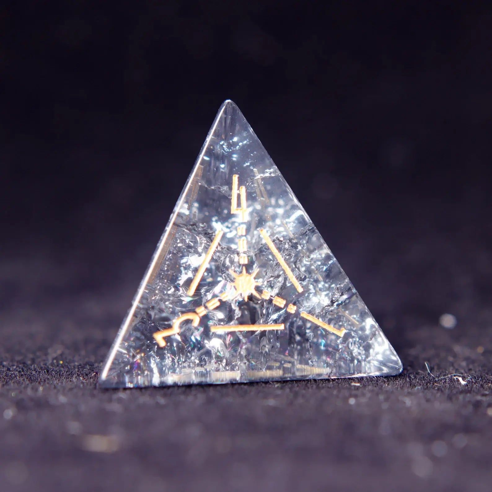 Single Black Crystal D4 dice with sharp edges and gold numbers, isolated on dark background