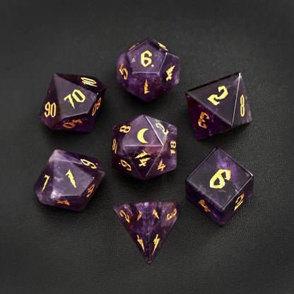 Complete 7-piece set of amethyst gemstone DND dice featuring gold lunar motifs, arranged on a black leather backdrop for a luxury tabletop gaming aesthetic.