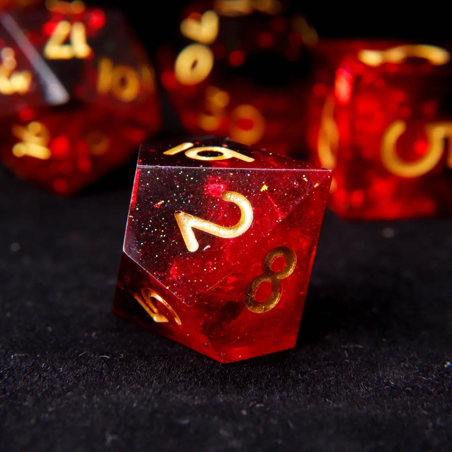 A hand holding several pieces of the fiery red sharp edge resin dice set, showcasing their polished texture and size.