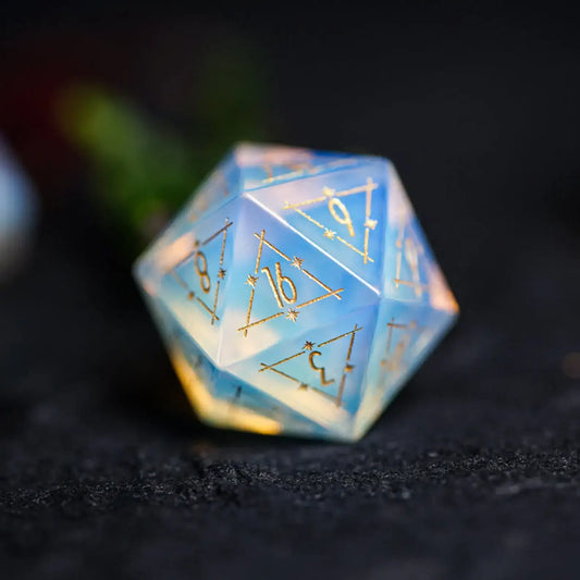Close-up of an engraved Opalite D20 die with star and moon astrology symbols.