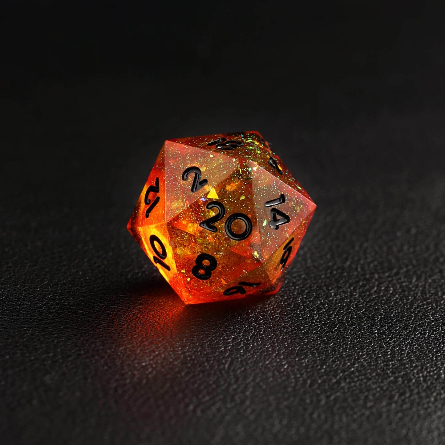Top view of orange red D20 dice with sharp edges reflecting light