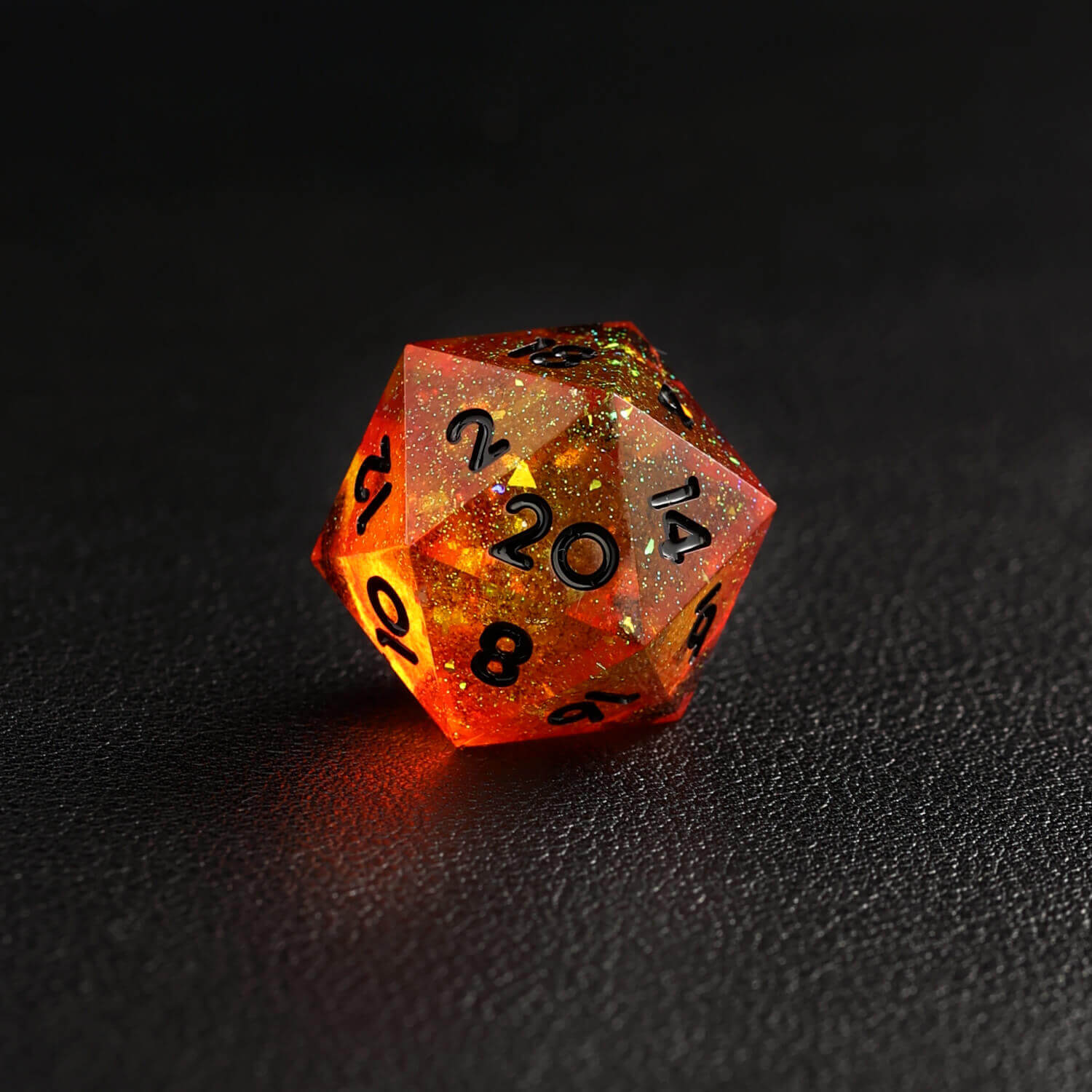 Top view of orange red D20 dice with sharp edges reflecting light
