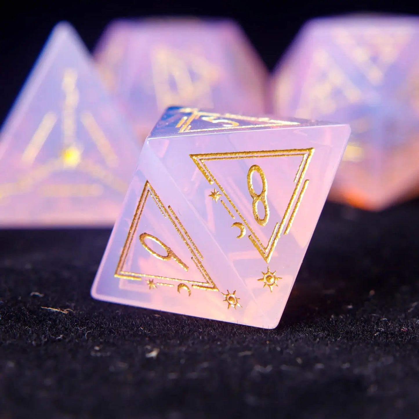 Pink carved opal D4 triangular die with soft glowing opal streaks.