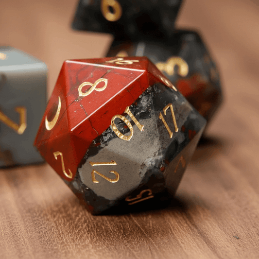 Close-up of a single engraved Grey Bloodstone D20 die on a walnut wood table.