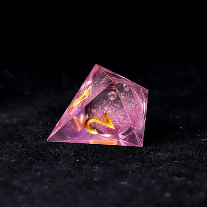 Translucent pink liquid core dice captured under backlighting, showcasing the crystal-clear resin and precision-centered core.